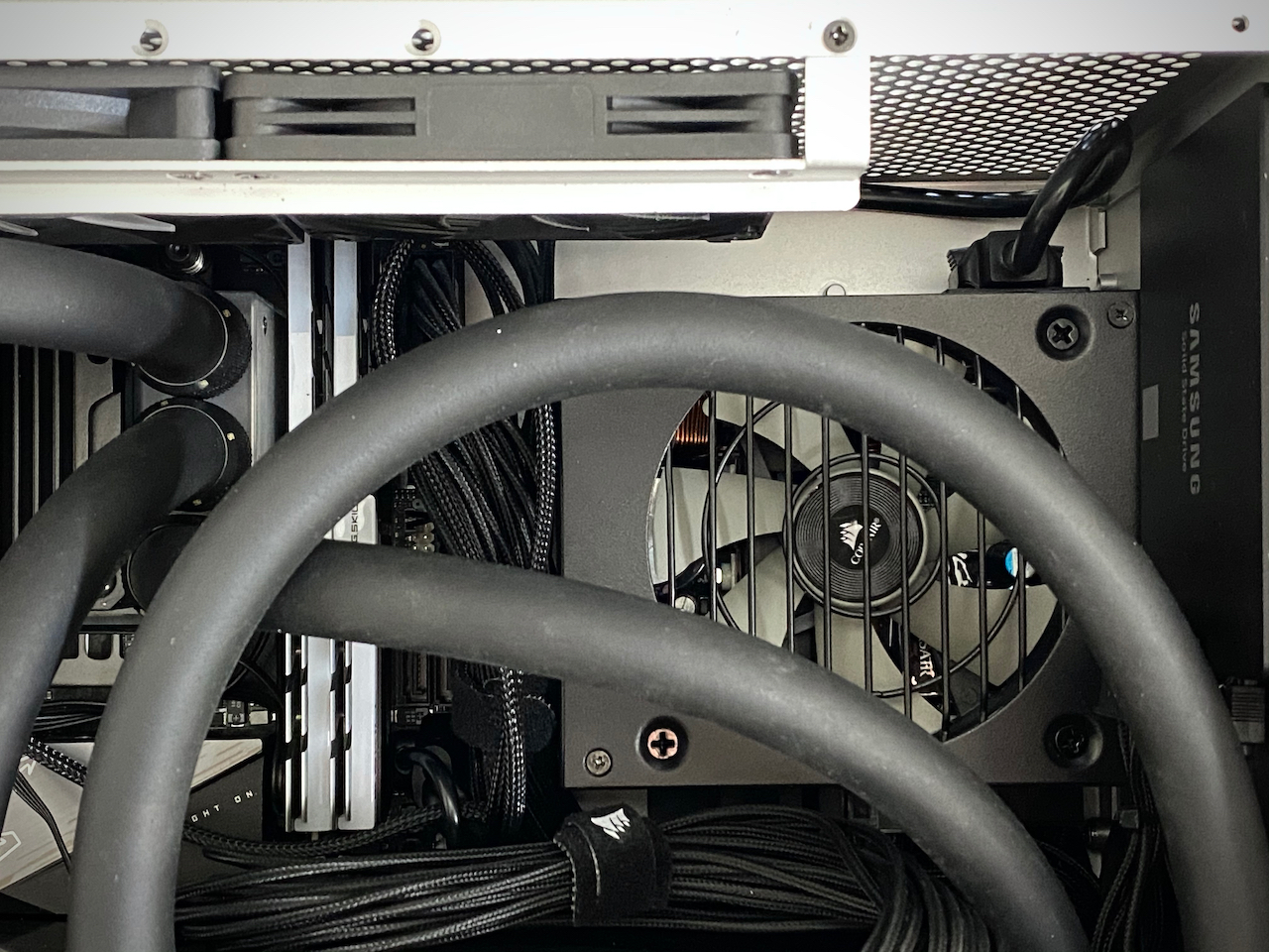 Close up picture of the power supply mounted on the back panel of the case in the upper right corner, seen behind the black water tubing.